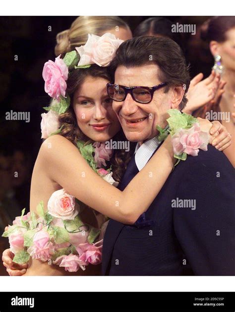 Model Laetitia Casta (L) hugs fashion designer Yves Saint 